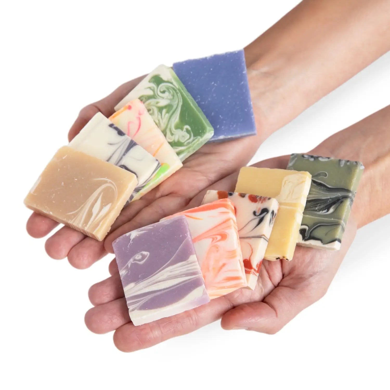 Hands holding soap sample bars with different colors and designs.