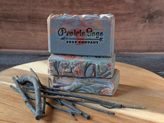 Bars of Bonfire handmade soap on a wooden platform with twigs in front of them.