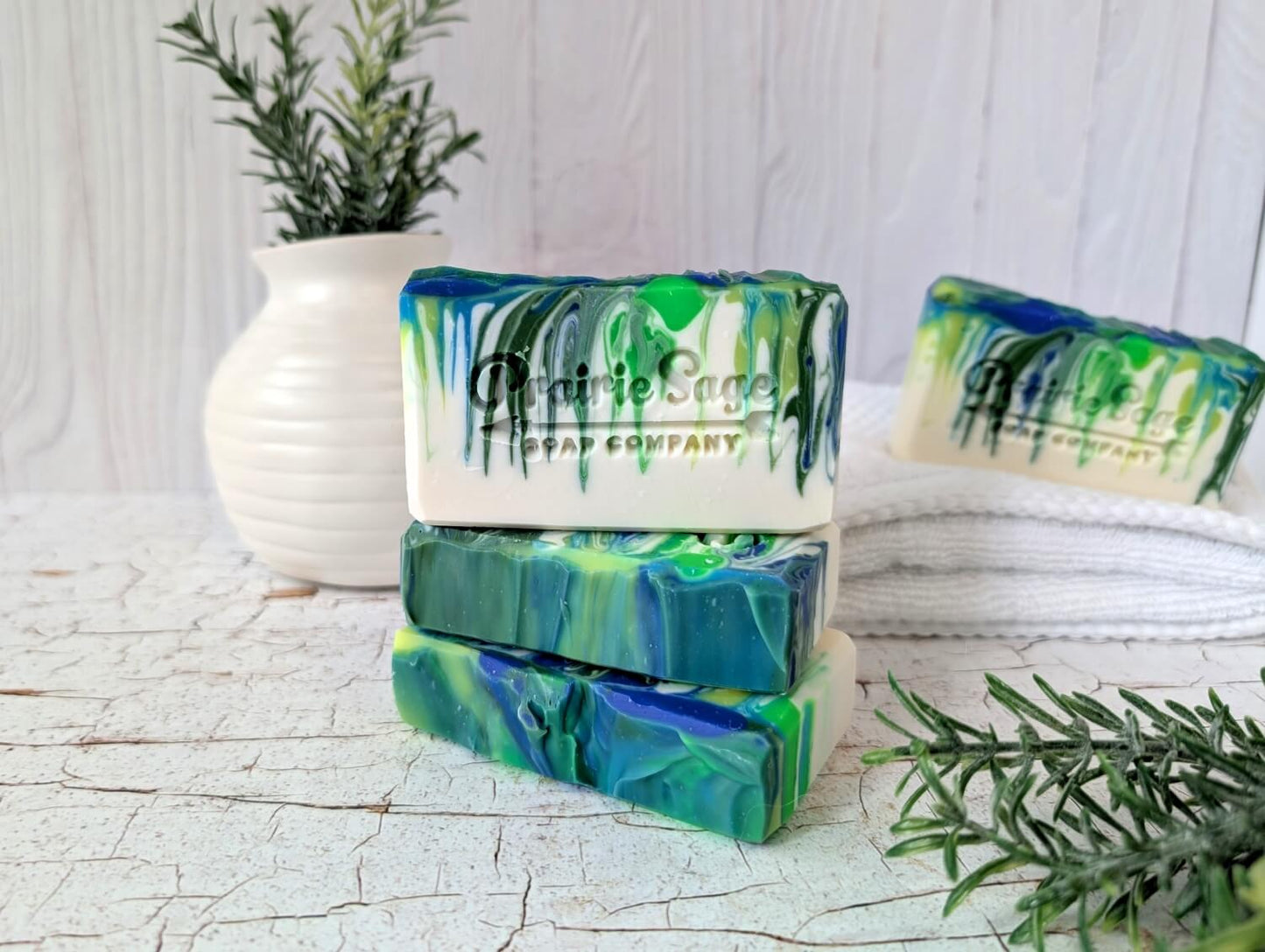 Emerald Mist bar soap stacked on each other on a cracked wood table.