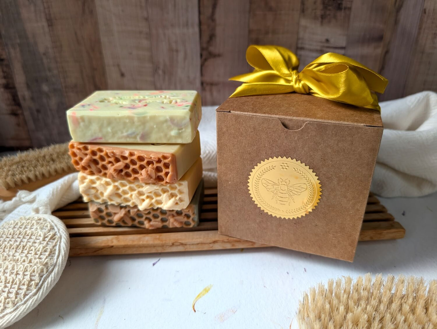 The Honeybee Apothecary box next to the four soaps included stacked on top of each other.