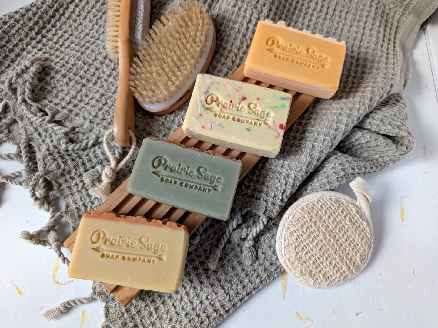 All four scents in the Honeybee Apothecary soap box laid out on a wooden tablet.