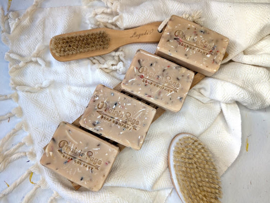 Four bars of Tea Tree and Red Clay soap sitting on a wooden board with a white blanket underneath.