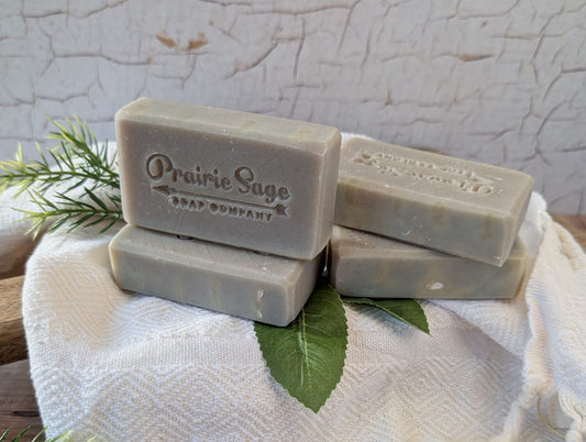 Bars of Wildcrafted Mint handmade soap on a white towel with leaves under them.