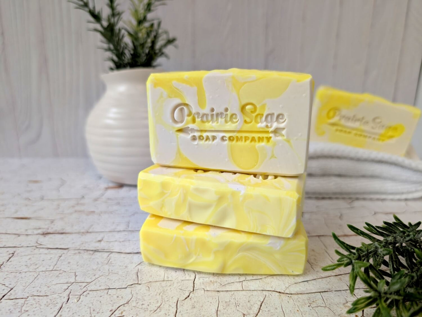 Yellow soap bars with 'Prairie Sage Soap Company' branding on a light wooden surface.